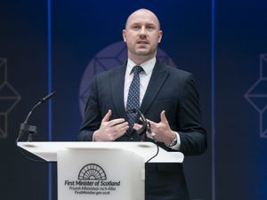 Neil Gray making a speech at a podium
