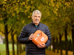 Stephen Lappin smiling while holding a defibrillator