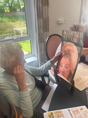 Resident looking at vintage magazine at HC-One’s Priorslee House Care Home from the Boots memory boxes