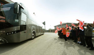 Schoolchildren cheer the coach as it pulls away