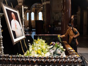 A woman lays flowers in front of a picture of Pope Francis at Westminster Cathedral in London