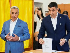 Calin Georgescu, winner of the first round of last year’s annulled election, left, stands next to Presidential candidate George Simion as they cast their votes in Mogosoaia