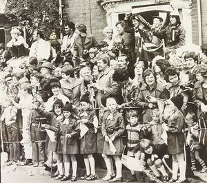 Crowds gathered with flags, including Brownies, waiting for Her Majesty the Queen who was visiting Sandwell in July 1977.