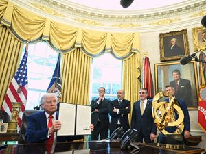 Donald Trump holding an executive order in the Oval Office
