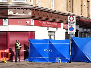 Police barriers outside a building, with an officer manning the cordon