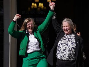 Susan Smith, left, and Marion Calder smiling and celebrating with their arms in the air