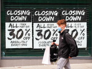 Customers walk past a closing down sale outside a retail premises (PA)