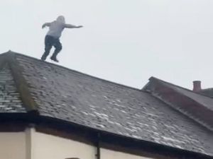 Shocking footage shows the moment a man began "launching tiles at emergency services" after clambering onto a roof during a tense standoff with police in Birmingahm. 
