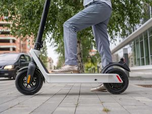 Legs of person standing by an e-scooter