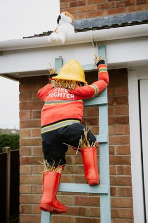 A helpful scarecrow rescuing a cat