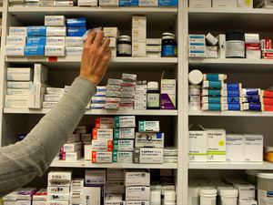 The arm of a pharmacist stocking shelves