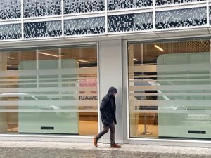 A man walks past the headquarters of Huawei in Brussel