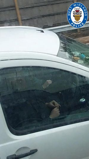 A driver rolling a suspected cannabis joint while driving