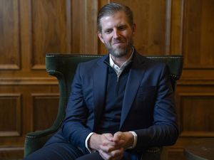 Eric Trump smiling, while seated in a wood-panelled room