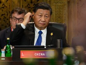 President Xi Jinping adjusting an ear piece during a meeting