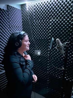 A young artist records vocals in the studio booth