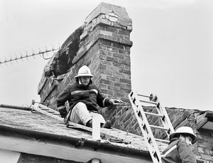 A firefighters helps secure an unsafe chimney