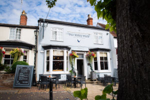 Exterior view of The Abbey Field pub in Kenilworth, with outdoor seating, hanging baskets and a painted facade