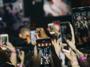 People holding their phones up at an event. A council says they should enjoy the moment instead