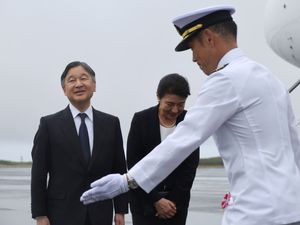 Japanese Emperor Naruhito, left, and Empress Masako are escorted by a member of Japan Self Defence Force as they arrive at the island of Iwo Jima, now officially called Iwo To