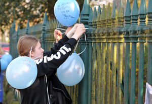 Bethany Zielinskj tying a balloon to the fence of West Park in memory of Viktorija