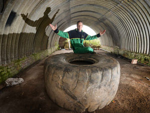 Chris Inett with a giant tyre dumped on his land