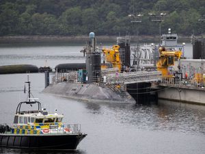 Submarine docked, with a police boat in the foreground