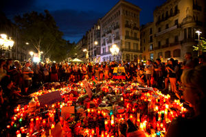 People gather around a memorial tribute of flowers, messages and candles on Las Ramblas