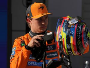 Oscar Piastri looks inside his helmet