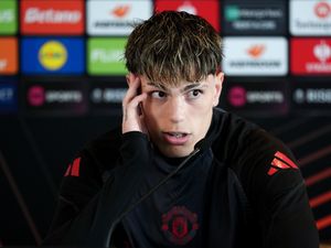 Alejandro Garnacho scratches his head while talking to the media