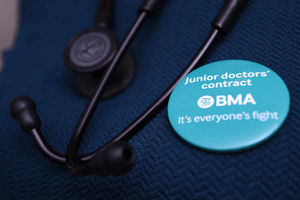 A doctor wears a badge next to her stethoscope in support of junior doctors