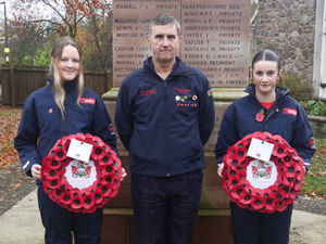 Fire service cadets Amelia Games and Emilia Shepherd with Presteigne firefighter Chris Chepherd at the war memorial. Pic by Karen Compton