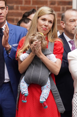 Carrie Johnson holding her daughter Romy watched Prime Minister Boris Johnson read his statement outside 10 Downing Street