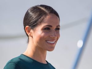 Headshot of the Duchess of Sussex smiling, wearing a green top