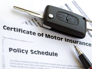 A car key on top of a Certificate of Motor Insurance and Policy Schedule
