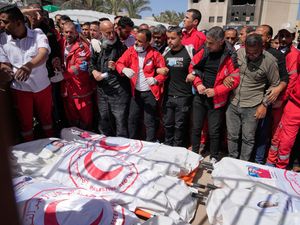 Mourners gather around the bodies of eight Red Crescent workers