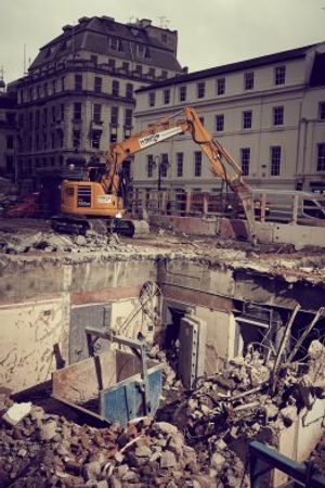 A digger gets to work dismantling the vaults from above.