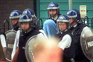 Police escort the attacker, covered by a blanket, from Villiers House near St Luke's