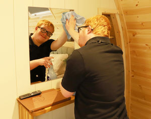 Tom cleaning a mirror inside one of the holiday lodges at the Ellesmere-based business.