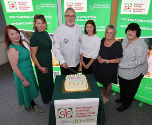 Cambrian Training Company directors Faith O’Brien, Elen Rees, Anne Jones, Angela Maguire-Lewis and Emma Morris with Arwyn Watkins, OBE, cutting the 30th anniversary cake