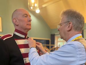 A tailor adjusts the uniform of a member of the Hillsborough Fort Guard