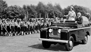 May 24, 1962. The caption reads: 'The Queen stands in a Land Rover as it drives slowly through Walsall Arboretum where 5,000 member of local youth organisations were gathered.'  