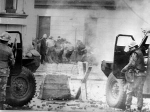 Soldiers take cover behind their sandbagged armoured cars (PA)