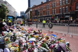 Floral tributes and crowds gathering at the Black Sabbath Bridge bench