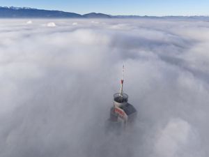 A tall building peaks through a dense layer of fog and smog in Sarajevo, Bosnia