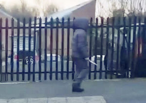 Chilling footage captures the moment a hooded knifeman casually walked down the street while brandishing a huge blade near a primary school. SWNS