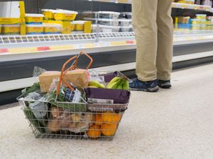 A shopping basket beside a man's feet