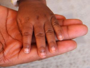 A baby holding their mother's hand
