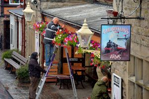 Station master Chris Thomas up the ladder, is helped by staff preparing Severn Valley Railway
