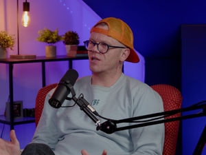 Darren McGarvey pictured seated, speaking with a microphone in front of him